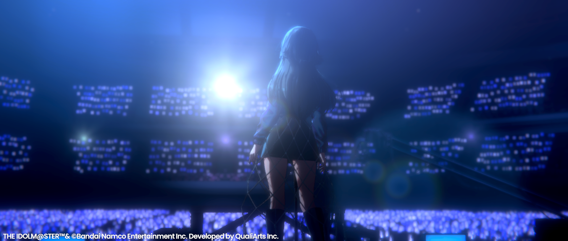 A girl pictured from her back, in front of her are thousands of audience and spotlights.